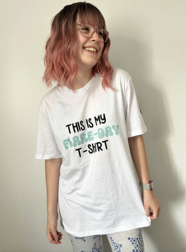 Woman with pink hair, wearing a white t-shirt that says 'this is my flare-day t-shirt'